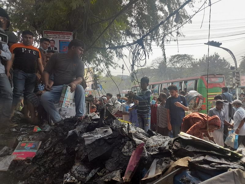 মো. জহির সকাল থেকে পুড়ে যাওয়া বইয়ের ধ্বংসস্তূপের ওপর বসে বই বিলান