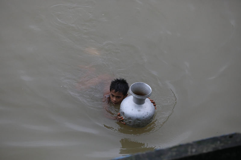 বিশুদ্ধ পানির সংকটে সিলেটের বানভাসি মানুষ। পানি আনতে আশ্রয়কেন্দ্র থেকে সাঁতার কেটে মূল সড়কের দিকে যাচ্ছে শিশু মইনুল। থানাবাজার, কোম্পানীগঞ্জ, সিলেট, ২০ জুন