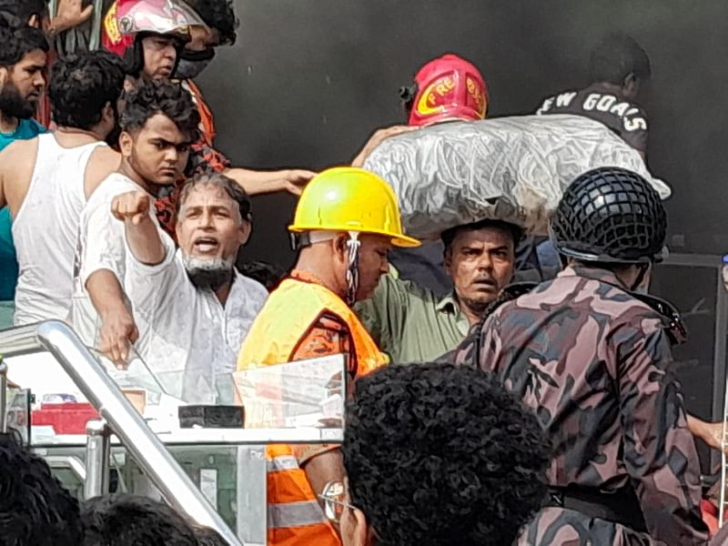 ঝুঁকি নিয়ে দোকান থেকে মালামাল বের করে নিয়ে আসছেন একজন ব্যবসায়ী