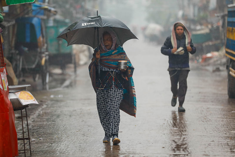 শীত ও বৃষ্টি মাথায় নিয়ে কাজে বের হওয়া মানুষ। ১৮ জানুয়ারি, ২০২৪