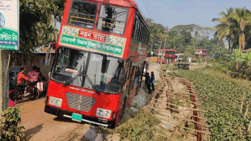 সড়কের পাশে বালুতে দেবে গেছে বাসের চাকা। রোববার সকালে নোয়াখালী শহরের দক্ষিণ সোনাপুর এলাকায়