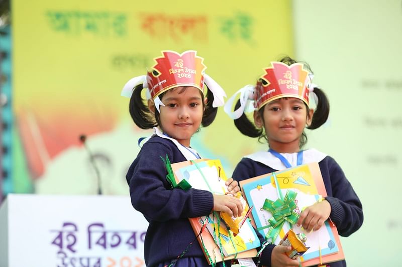 নতুন বছরের পাঠ্যপুস্তক বিতরণ কার্যক্রম বই বিতরণ উৎসবে নতুন বই পেয়ে আনন্দিত যমজ বোন সুবা আর তুবা। ন্যাশনাল সরকারি প্রাথমিক বিদ্যালয়ের শিশুশিক্ষার্থী ওরা। ন্যাশনাল সরকারি প্রাথমিক বিদ্যালয় প্রাঙ্গণ, মিরপুর-২, ঢাকা, ১ জানুয়ারি