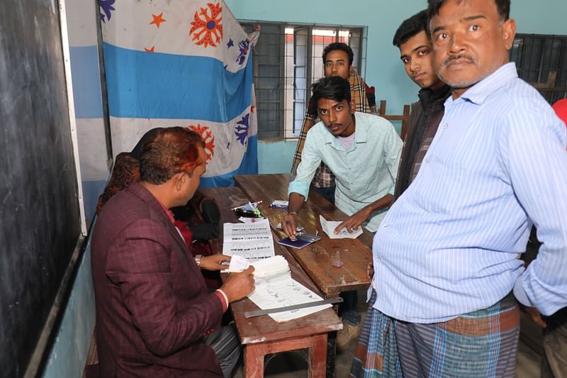 বগুড়া-১ আসনে সারিয়াকান্দি সরকারি বালক উচ্চবিদ্যালয় কেন্দ্রে সহকারী প্রিসাইডিং কর্মকর্তা রিপন মিয়ার টেবিলে প্রকাশ্যে ভোট দিচ্ছেন এক ভোটার। রোববার দুপুরে