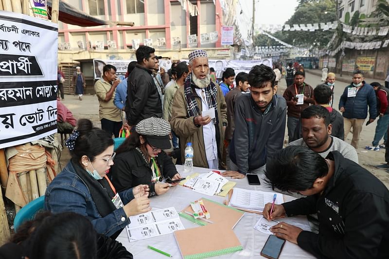 রাজধানীর যাত্রাবাড়ীতে সিটি করপোরেশন আদর্শ উচ্চবিদ্যালয়ের কেন্দ্রের বাইরে দায়িত্ব পালনরত নির্বাচনী কর্মকর্তারা। ধলপুর, যাত্রাবাড়ী, সকাল ৮টা ২৫ মিনিট