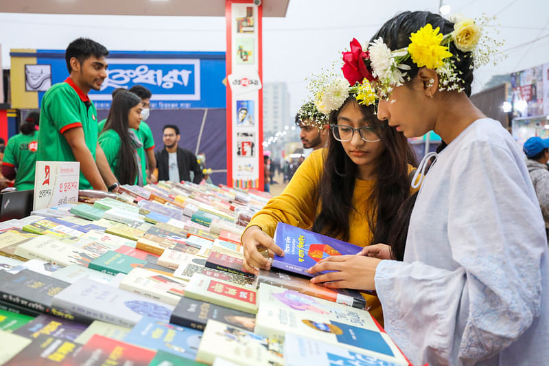 স্টলে পছন্দের বই দেখছে দুই পাঠক