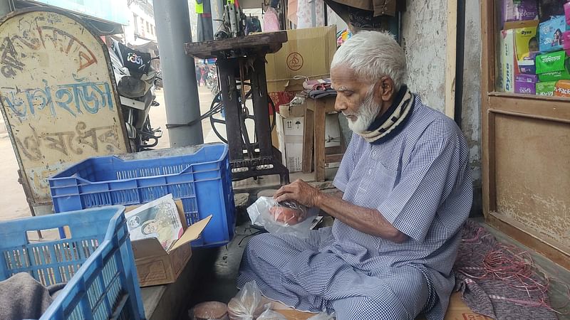 চাঁপাইনবাবগঞ্জের গোমস্তাপুর উপজেলার রহনপুর স্টেশন বাজারে পথের পাশে বসে দই ও ক্ষীর বিক্রি করছেন জিয়াউল হক। গতকাল বুধবার দুপুর সোয়া ১২টার দিকে