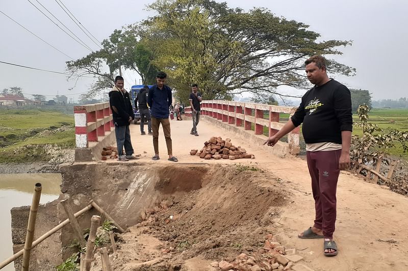 সেতুর সংযোগ সড়কের ধসে পড়া অংশ দেখছেন স্থানীয় কয়েকজন। আজ সোমবার সকালে সুনামগঞ্জের জগন্নাথপুর-শিবগঞ্জ-বেগমপুর সড়কের ঘোষগাঁও সেতু এলাকায়