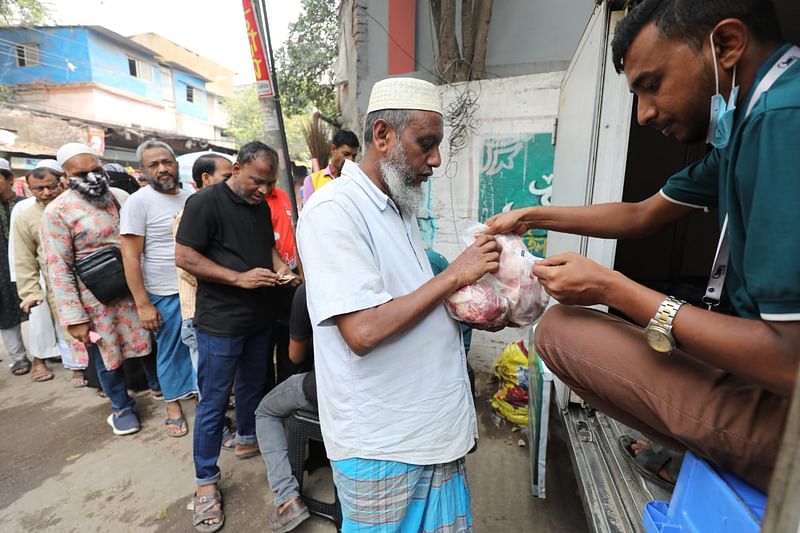 লাইনে দাঁড়িয়ে ভ্রাম্যমাণ ভ্যান থেকে সুলভ মূল্যে মাংস, ডিম ও দুধ কিনছেন ক্রেতারা। ১৯ মার্চ, নবাবগঞ্জ রোড, লালবাগ, ঢাকা