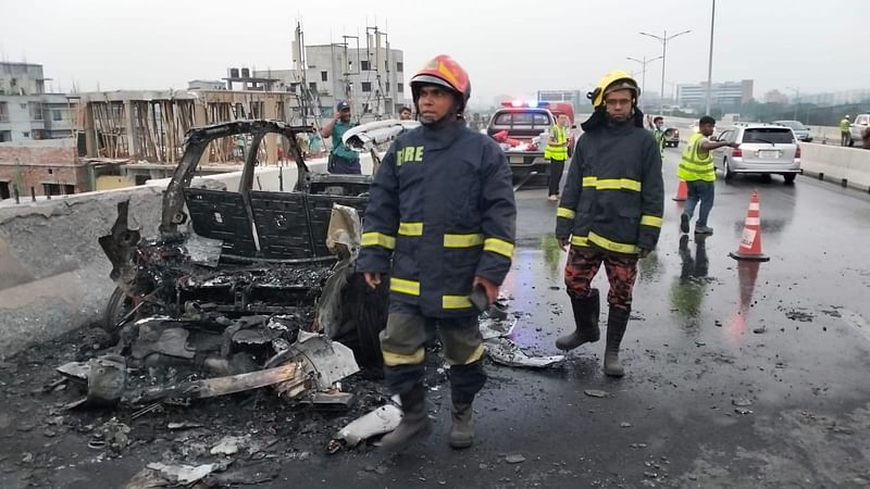 আগুন লেগে পুড়ে যাওয়া গাড়িটির পাশে ফায়ার সার্ভিসের কর্মীরা