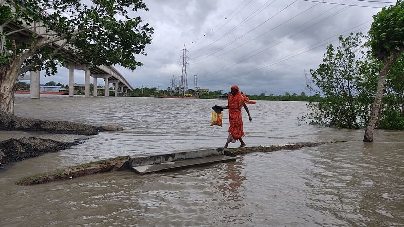 ঘূর্ণিঝড় রিমালের প্রভাবে উপকূলের নদ-নদীর পানি বেড়ে তলিয়ে গেছে তীরবর্তী এলাকা। ঘরে পানি ওঠায় আশ্রয়কেন্দ্রে যাচ্ছেন এক নারী। রোববার দুপুরে বাগেরহাট সদর উপজেলার দড়াটানা নদীর তীরবর্তী পুরাতন ফেরিঘাটে এলাকায়