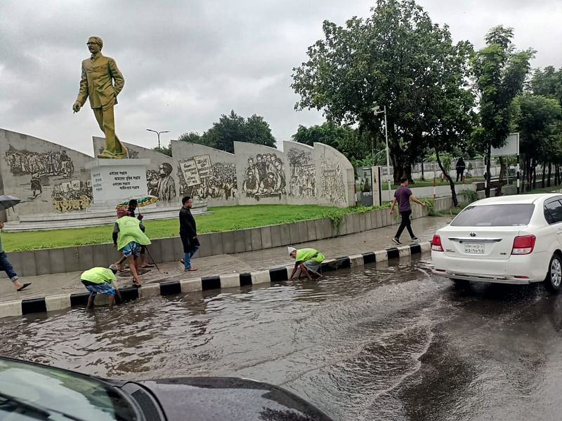 সড়কে জমে থাকা পানি অপসারণ করছেন ঢাকা উত্তর সিটি করপোরেশনের (ডিএনসিসি) কর্মীরা। ঢাকা, ২৭ মে