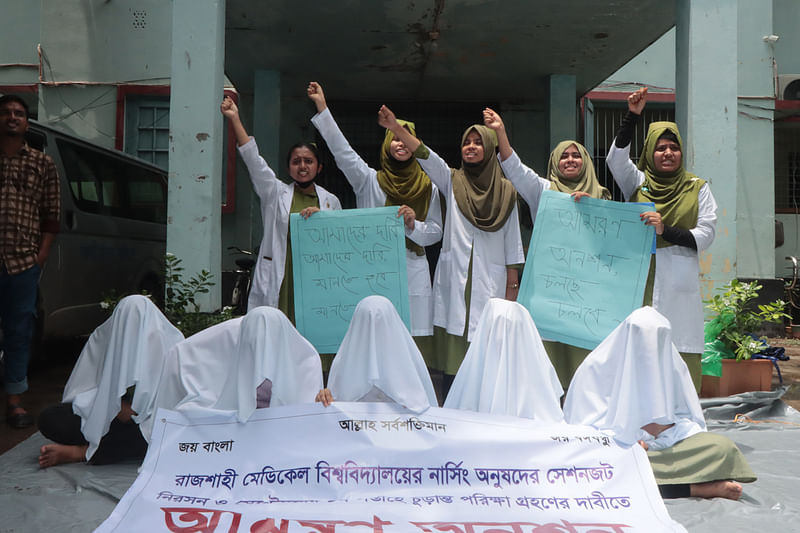 রাজশাহী মেডিকেল বিশ্ববিদ্যালয়ের পরীক্ষা নিয়ন্ত্রণ ও কলেজ পরিদর্শকের দপ্তরের সামনে কাফনের কাপড় নিয়ে বিক্ষোভ ও অনশনে অধীন নার্সিং কলেজের শিক্ষার্থীরা। বুধবার দুপুরে তোলা