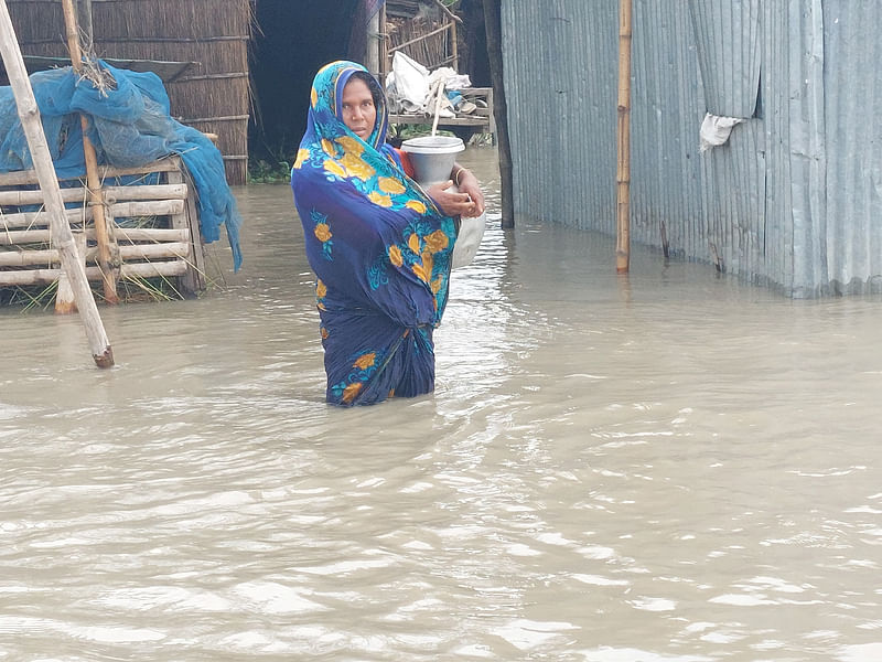 বন্যায় নলকূপ ডুবে যাওয়ায় গৃহবধূ সাহেরা বেগম কলসি নিয়ে বিশুদ্ধ পানি আনতে যাচ্ছেন। আজ দুপুরে গাইবান্ধার সুন্দরগঞ্জ উপজেলার ভাটি বোচাগাড়ি গ্রামে