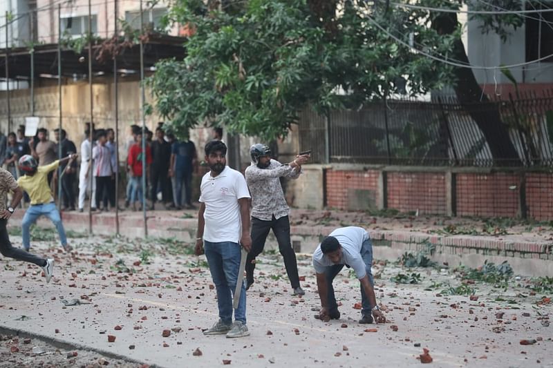 আন্দোলনকারী শিক্ষার্থীদের লক্ষ্য করে আগ্নেয়াস্ত্র তাক করে আছেন এক তরুণ। আজ সোমবার বিকেলে শহীদুল্লাহ হল এলাকায়