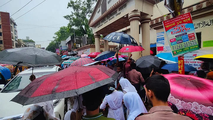 মিডিয়া গ্যালারি থেকে (বৃষ্টি বাড়তে থাকলে পরীক্ষাকেন্দ্রের ফটকে ঢোকার জন্য ব্যস্ত হয়ে যান পরীক্ষার্থী ও অভিভাবকেরা। মোহাম্মদপুর কেন্দ্রীয় বিশ্ববিদ্যালয় কলেজের সামনে