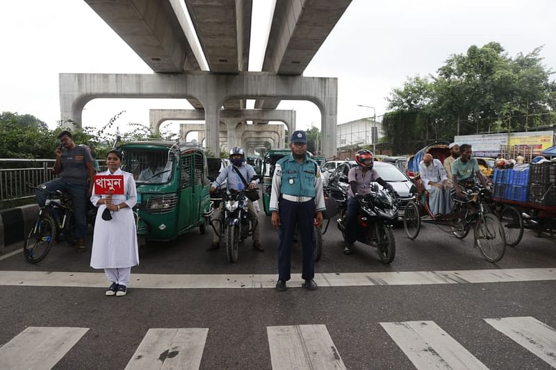 রাজধানীর আগারগাঁও এলাকায় দায়িত্বপালন করছে ট্রাফিক পুলিশ। সঙ্গে শিক্ষার্থীরাও রয়েছে।