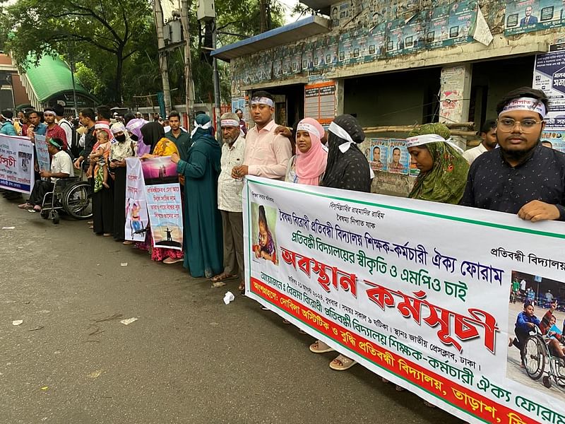 ‘বৈষম্যবিরোধী প্রতিবন্ধী বিদ্যালয় শিক্ষক-কর্মচারী ঐক্য ফোরাম’–এর ব্যানারে শিক্ষক-কর্মচারীরা জাতীয় প্রেসক্লাবের সামনের সড়কে অবস্থান ও মানববন্ধন করছেন। ঢাকা, ২২ আগস্ট