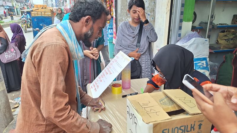 রাজশাহী নগরের অলকার মোড়ে বন্যার্তদের সহযোগিতা খোলা বুথে সহায়তা করছেন নানা শ্রেণি–পেশার মানুষ