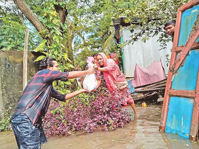 বন্যায় পানিবন্দী এক নারীর হাতে প্রথম আলো ট্রাষ্টের পক্ষ থেকে দেওয়া ত্রাণ তুলে দেওয়া হচ্ছে। গতকাল দুপরে নোয়াখালী সদর উপজেলার কাদিরহানিফ ইউনিয়নের নিত্যনন্দপুর গ্রামে