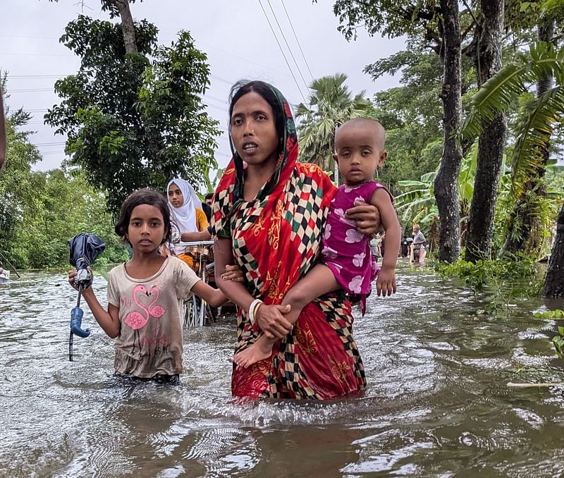 বন্যায় পানি মাড়িয়ে শিশুদের নিয়ে যাচ্ছেন এক অভিভাবক