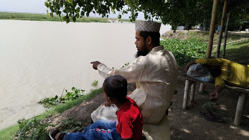 রাজশাহী নগরের ফুদকি পাড়া এলাকায় দুই শিশুসন্তানকে পদ্মার পানি দেখাচ্ছেন রাজশাহী আঞ্চলিক শিক্ষা কার্যালয়ের একজন কর্মকর্তা। আজ শনিবার দুপুর ১২টার দিকে