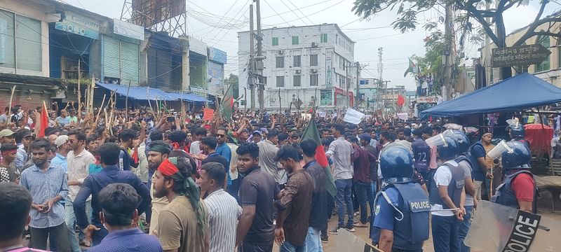 জয়পুরহাট শহরের পাঁচুর মোড়ে বিক্ষোভকারীরা। পাশেই আইনশৃঙ্খলা রক্ষাকারী বাহিনী। আজ বেলা সাড়ে ১১টায় তোলা