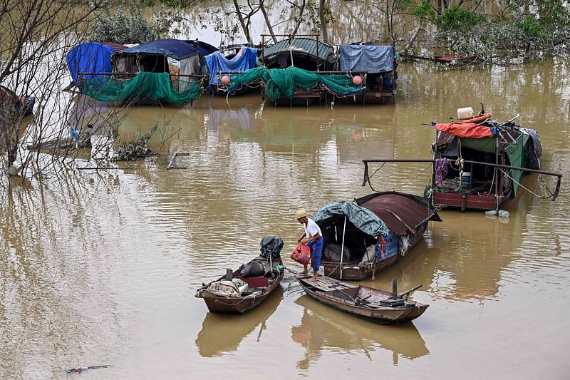 বন্যার পানি কমায় নৌকা নিয়ে স্বাভাবিক কাজ শুরু চেষ্টা করছেন মানুষ। ভিয়েতনামের রাজধানী হ্যানয়ের রেড নদীতে, ১৩ সেপ্টেম্বর ২০২৪