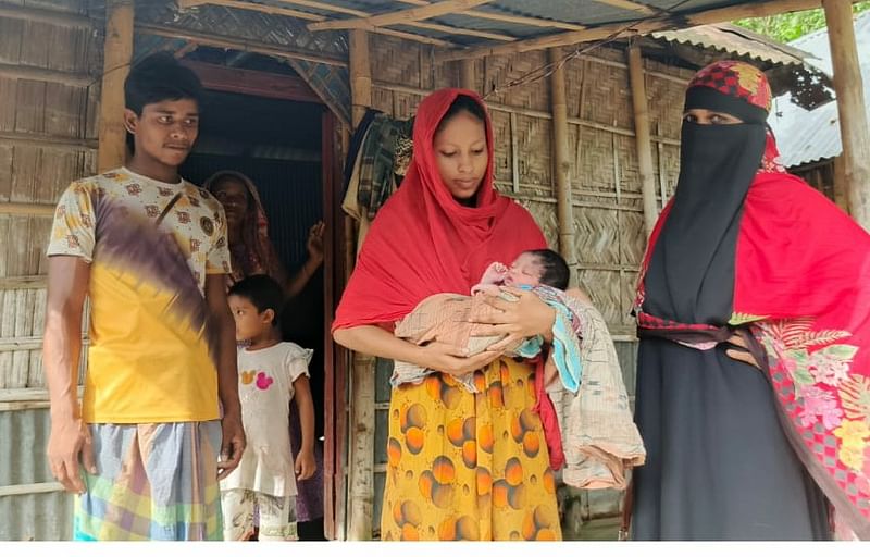 বদরগঞ্জ উপজেলার কুতুবপুরে নিজ বাড়িতে নবজাতককে কোলে নিয়ে দাঁড়িয়ে আছে মা মমতা বেগম