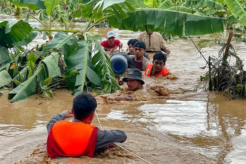 মিয়ানমারের নাইপিদো অঞ্চলের পিনমানা শহরে বুকসমান বন্যার পানি থেকে স্থানীয় বাসিন্দাদের উদ্ধার করছেন পুলিশ সদস্যরা