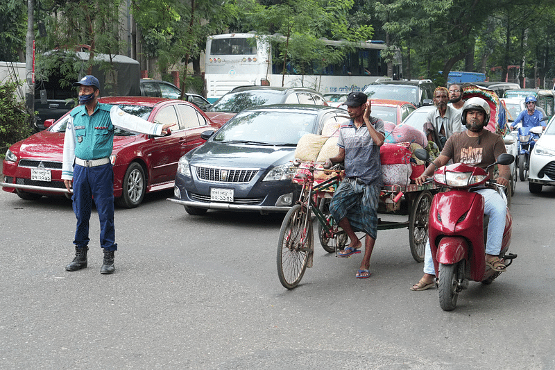 রাস্তায় যানবাহন নিয়ন্ত্রণ করছে ট্রাফিক পুলিশ