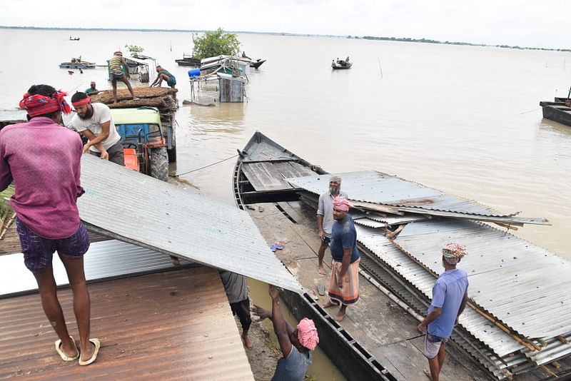 পদ্মা নদীর ভাঙনের কারণে বাড়িঘর ভেঙে নিয়ে যাচ্ছেন লোকজন। বৃহস্পতিবার দুপুরে রাজশাহীর গোদাগাড়ী রেলবাজার ঘাট এলাকায়