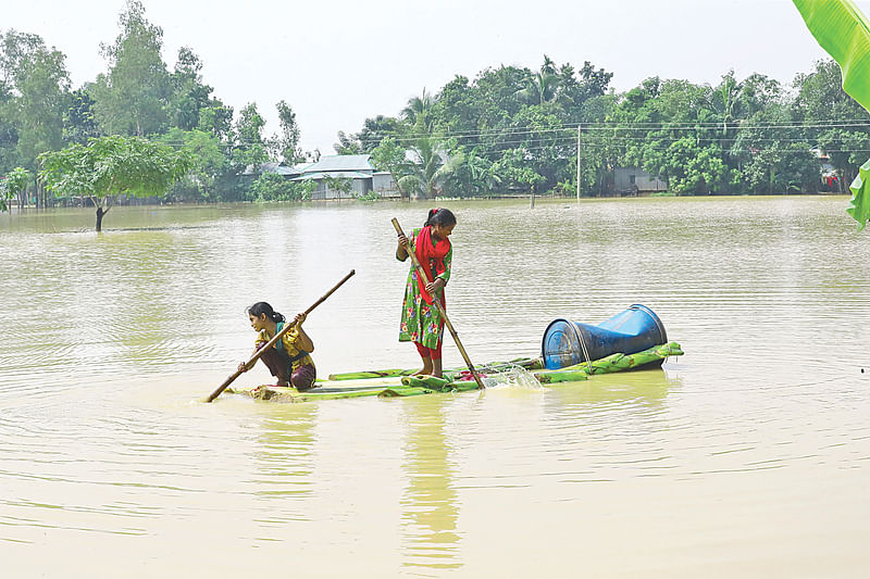 বন্যার পানিতে ভেলায় চড়ে যাচ্ছে দুই শিশু। গতকাল শেরপুরের নালিতাবাড়ীতে