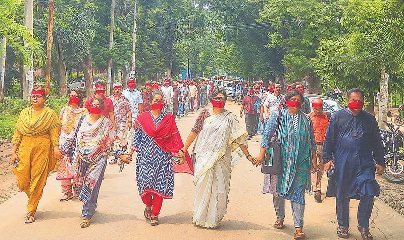 শিক্ষার্থীদের দাবির প্রতি সংহতি জানিয়ে মুখে লাল কাপড় বেঁধে ‘নিপীড়নের বিরুদ্ধে জাহাঙ্গীরনগর’–এর ব্যানারে শিক্ষকেরা। ৩০ জুলাই ২০২৪