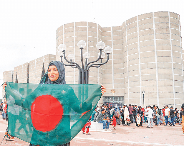 হাস্যোজ্জ্বল তরুণীর হাতে লাল–সবুজ পতাকা, চোখে নতুন স্বপ্ন। ৬ আগস্ট ২০২৪।