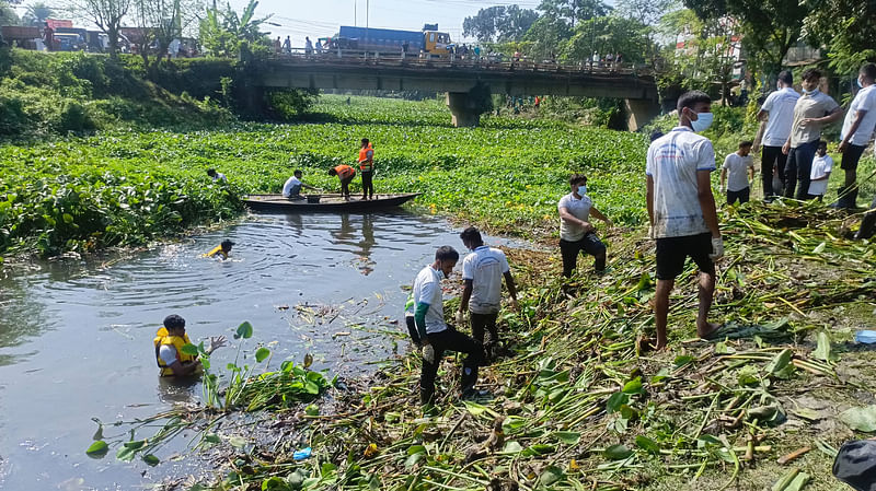 তুলসীগঙ্গা নদীর কচুরিপানা পরিষ্কার করছেন স্বেচ্ছাসেবীরা। শনিবার বেলা ১১টায় নওগাঁ শহরের রজাকপুর এলাকায়