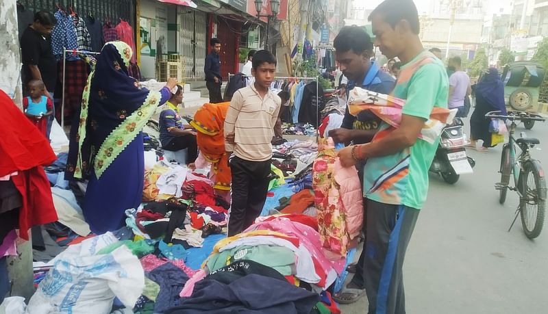 রাজশাহী নগরের ফুটপাতে বসেছে সাপ্তাহিক কাপড় বিক্রির হাট। এখানকার বেশির ভাগ ক্রেতা নিম্ন আয়ের। শুক্রবার বেলা ১১টার দিকে নগরের সাহেববাজার এলাকায়