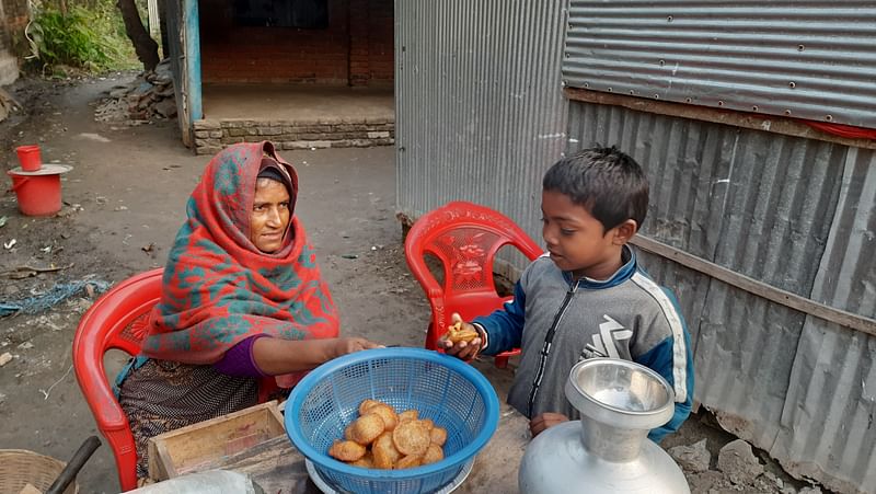 বিউটির বানানো পিঠা খেতে এসেছে এক শিশু। সোমবার সকালে যশোরের কেশবপুর উপজেলা শহরের বালিয়াডাঙ্গা বিশ্বাসপাড়ায়