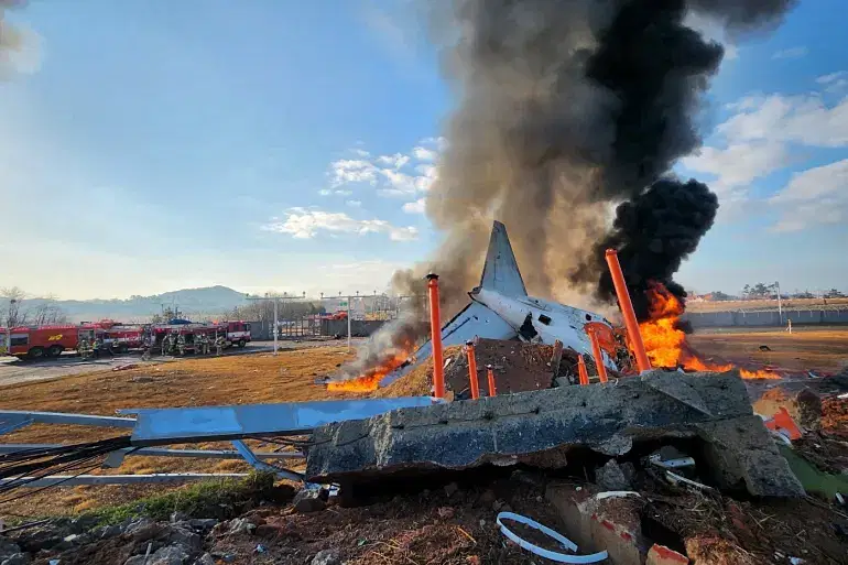 দক্ষিণ কোরিয়ার মুয়ান আন্তর্জাতিক বিমানবন্দরের রানওয়েতে বিধ্বস্ত উড়োজাহাজটিতে আগুন জ্বলছে। ২৯ ডিসেম্বর ২০২৪