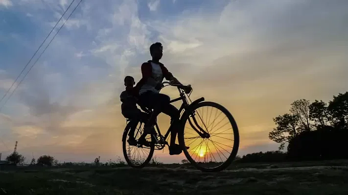 Two children ride a bicycle during sunset at Tetultola, Botiaghata, Khulna on 14 March 2020