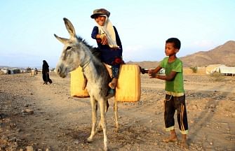 A girl rides a donkey carrying jerry cans filled with water from a cistern at a make-shift camp for displaced Yemenis in severe shortage of water, in the northern Hajjah province on 24 March, 2020.