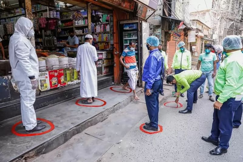 Cops draw circles indicating social distancing positions for customers in front of a shop at Kazi Alauddin Road, Bangshal in Dhaka on 28 March 2020.