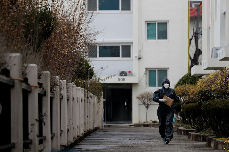 A worker in protective gear makes her way to an apartment building which has entered cohort isolation after a mass coronavirus infection was reported in Daegu, South Korea, on 7 March 2020