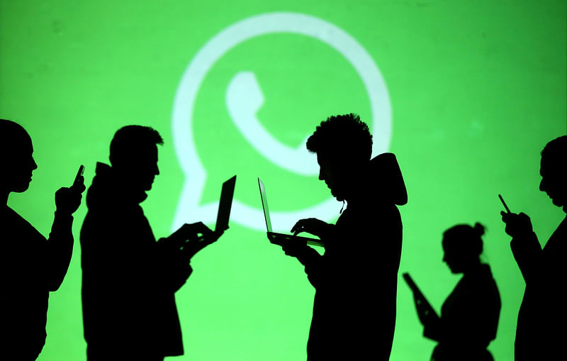 Silhouettes of laptop and mobile device users are seen next to a screen projection of Whatsapp logo in this picture illustration taken 28 March 2018