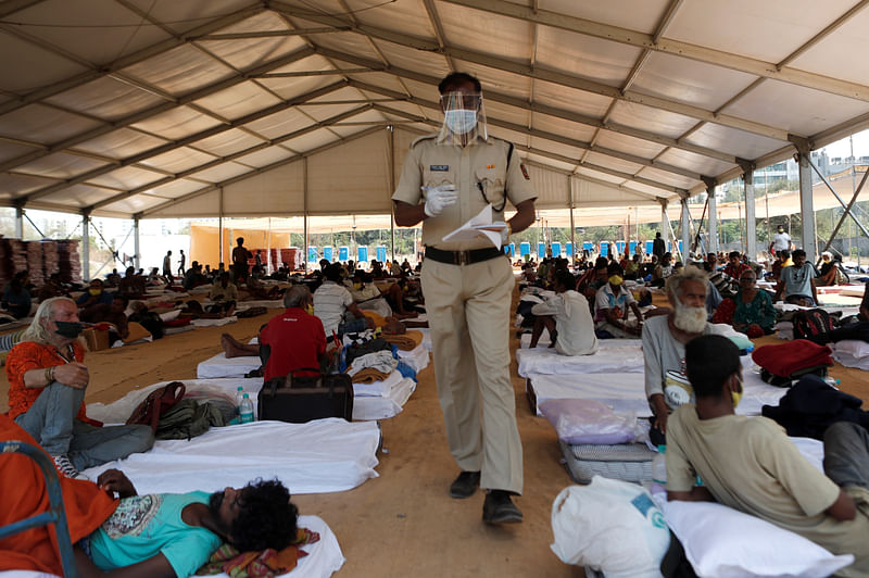 A policeman wearing a protective mask walks inside a shelter set up for migrants during a 21-day nationwide lockdown to limit the spreading of coronavirus in Mumbai, India.