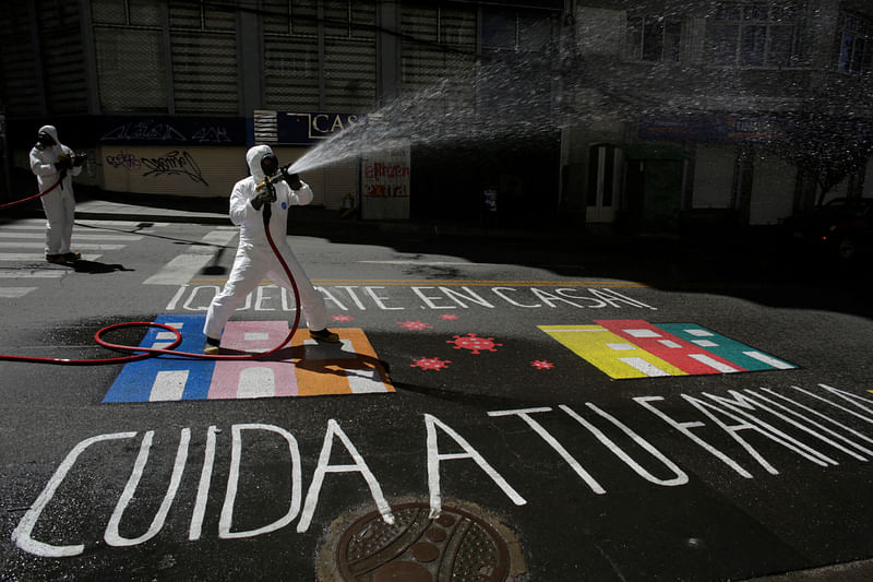 Public health workers use disinfectant to clean a street as a graffiti on the floor reads "Stay home, take care of your family" as the spread of the coronavirus disease (COVID-19) continues in La Paz, Bolivia.