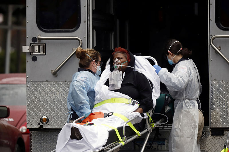 Emergency Medical Technicians (EMT) wearing protective gears wheel a sick patient to a waiting ambulance during the outbreak of coronavirus disease (COVID-19) in New York City.