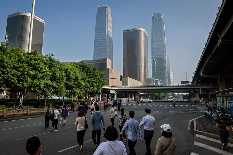 People commute across a street during the morning rush hour in Beijing on 22 May 2020, as they city hosts the opening session of the annual National People's Congress (NPC)