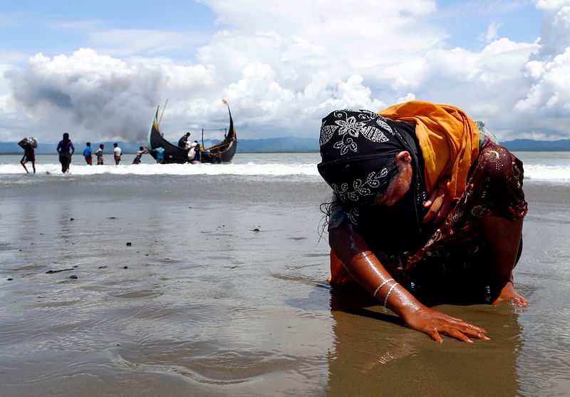 An exhausted Rohingya refugee woman touches the shore after crossing the Bangladesh-Myanmar border by boat through the Bay of Bengal in Shah Porir Dwip, Bangladesh, on 11 September 2017