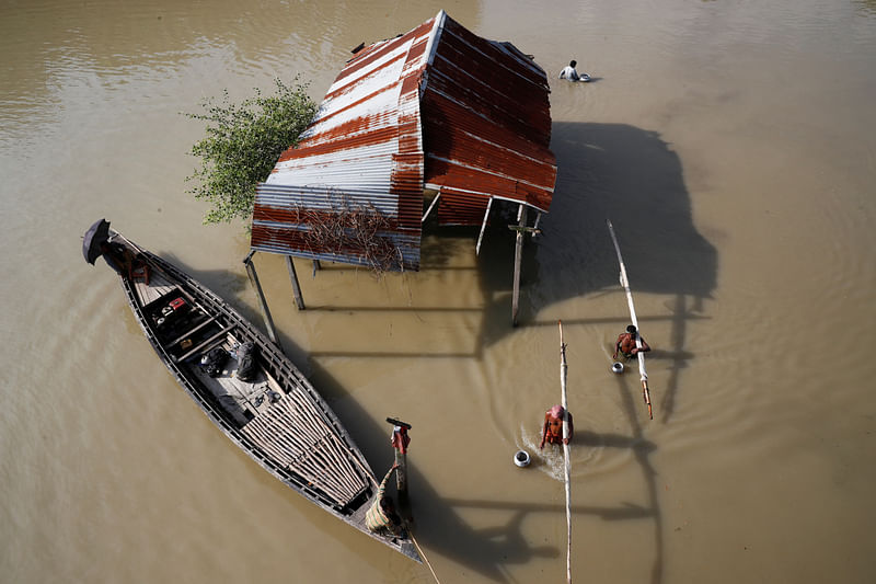 Fishermen wade through the water with their fishing nets in a flooded area in Jamalpur, Bangladesh, 18 July 2020.