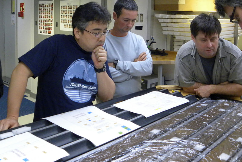 Researchers Yuki Morono, Laurent Toffin and Steven DÕHondt (L-R) work aboard the research drillship JOIDES Resolution with sediment cores gathered from deep beneath the seafloor under the Pacific Ocean in this undated photograph released on 28 July 2020.